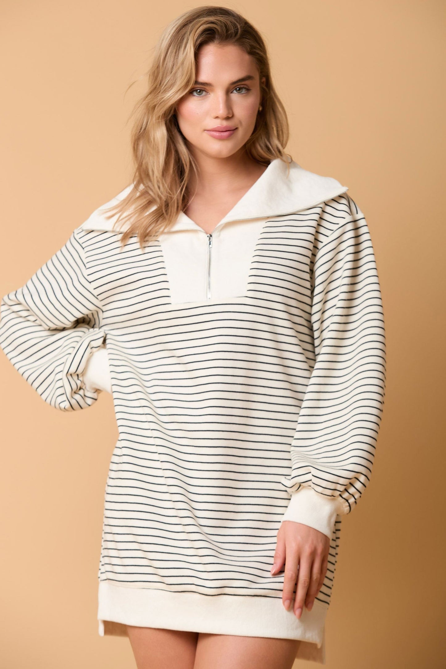Close up of a woman's hand in a striped sweater dress with ribbed cuffs.