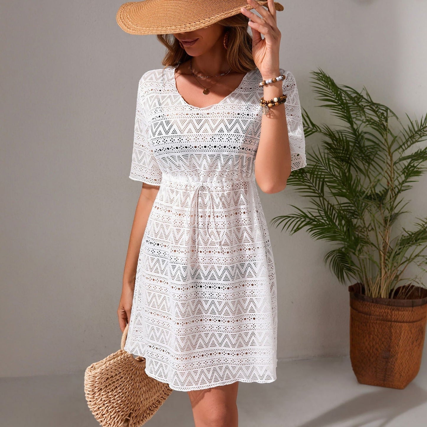 woman wearing a white lace cover-up dress with a straw hat and a straw bag