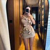 Woman in a beige crocheted halter top and mini skirt with floral appliques, taking a mirror selfie in a room with mirrors.