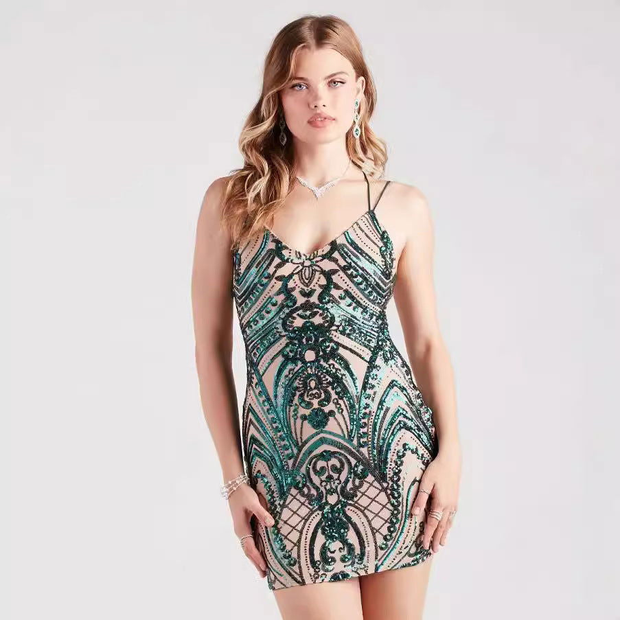 A young woman poses in a short, sequined dress with a V-neck and spaghetti straps. The dress features a green and black patterned sequin embellishment over a nude lining.