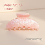 A pink pearlescent claw clip with text overlay indicating 'Pearl Shine Finish' and 'Soft & Dreamy Look'.