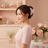 A woman in a pink dress smiling while wearing a pink claw clip in her hair.