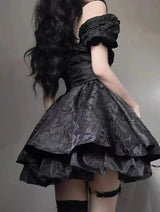 Back view of a woman wearing a black off-the-shoulder dress with a tiered skirt.