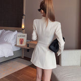 Back view of a woman in a beige blazer dress.