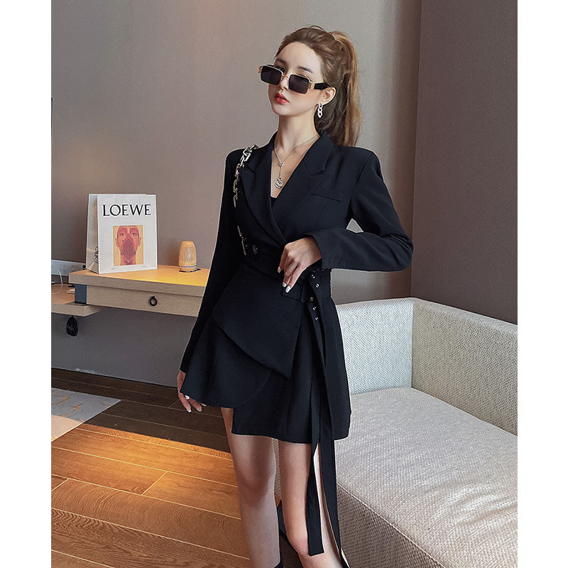 A woman in a black blazer dress with sunglasses and a black handbag.