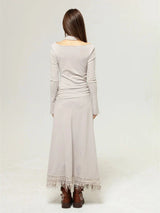 Back view of a woman in a beige long-sleeved dress with a floral print and a layered top, paired with brown boots.
