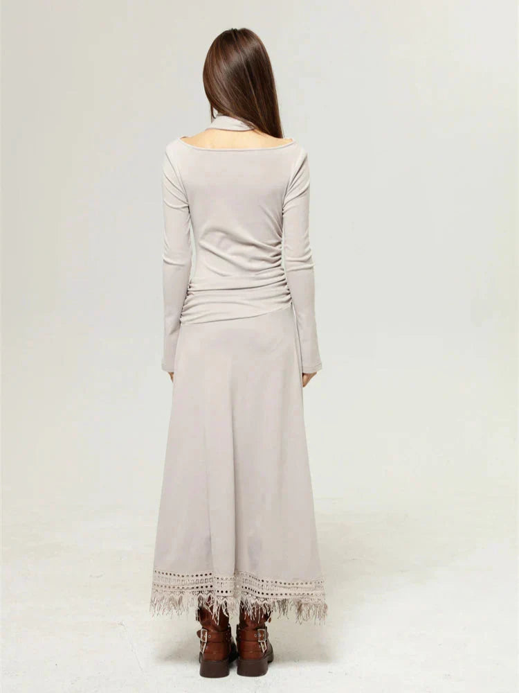 Back view of a woman in a beige long-sleeved dress with a floral print and a layered top, paired with brown boots.