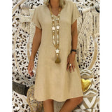 woman wearing a beige short-sleeve v-neck dress with a long tassel necklace