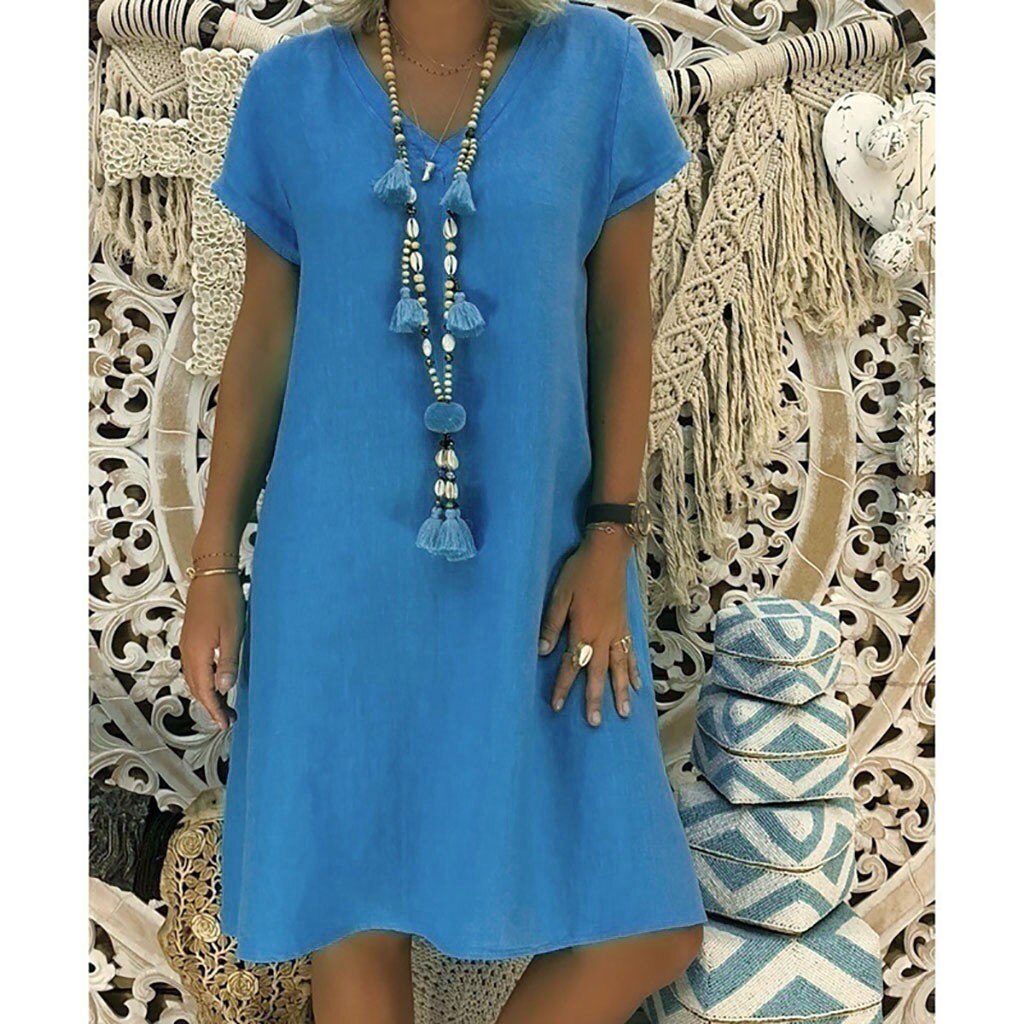 woman wearing a blue short-sleeve v-neck dress with a long tassel necklace