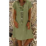 woman wearing a green short-sleeve v-neck dress with a long tassel necklace