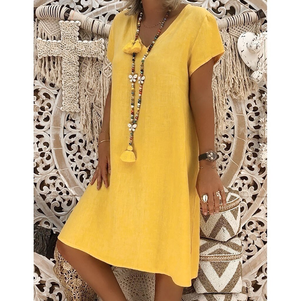 woman wearing a yellow short-sleeve v-neck dress with a long tassel necklace