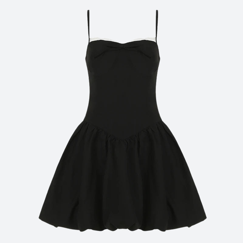 A black spaghetti strap dress with a white lace trim and a bow detail, laid flat.
