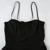 Close-up of the bodice of a black spaghetti strap dress, showing the white lace trim and bow detail.