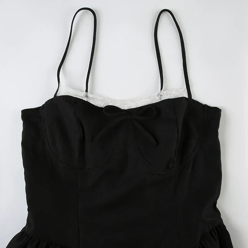 Close-up of the bodice of a black spaghetti strap dress, showing the white lace trim and bow detail.