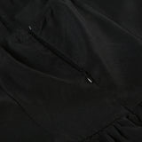 Close-up of the zipper closure on the back of a black dress.