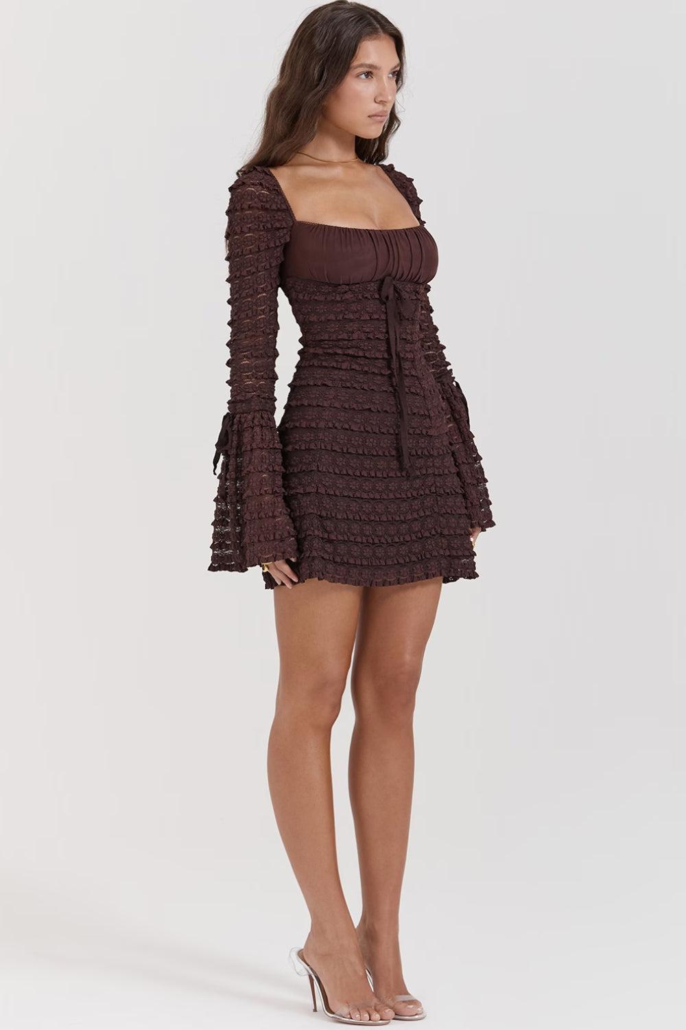 Side view of a woman wearing a short, brown, long-sleeved ruched dress with a square neckline and bell sleeves.
