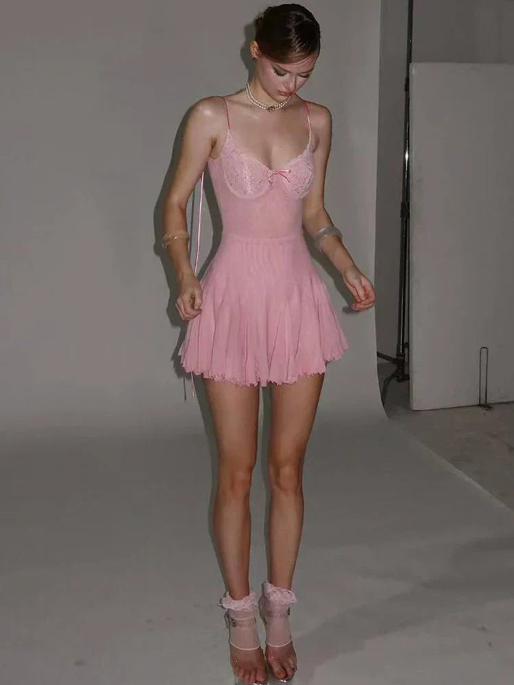 A full-body shot of a young woman wearing a pink slip dress and sheer socks.