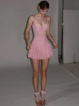 A full-body shot of a young woman wearing a pink slip dress and sheer socks.
