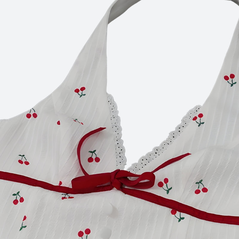 Close-up of the neckline of a white cherry print halter dress with red ribbon and lace trim.