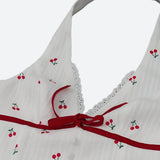 Close-up of the neckline of a white cherry print halter dress with red ribbon and lace trim.