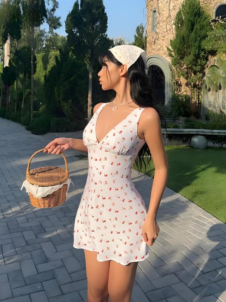 A woman in a white cherry-print mini dress, white bandana, and holding a wicker basket