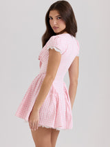 A woman from behind in a pink and white gingham dress with short sleeves and lace trim.