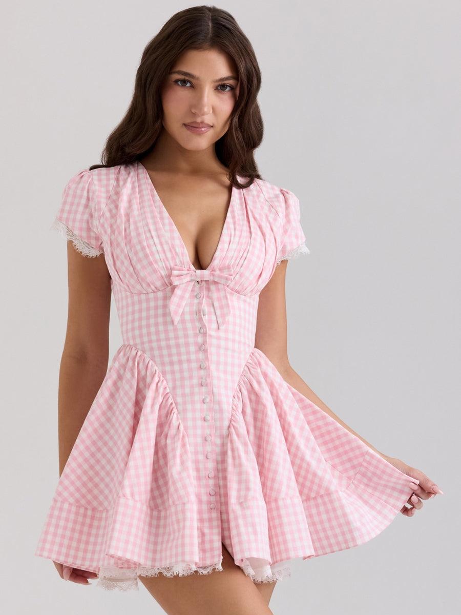 A woman in a pink and white gingham dress with a v-neckline and button front.