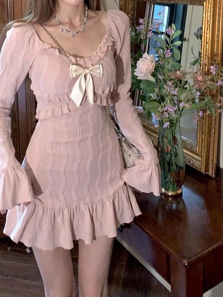 Close-up of a woman in a pink dress with a bow and ruffled neckline.