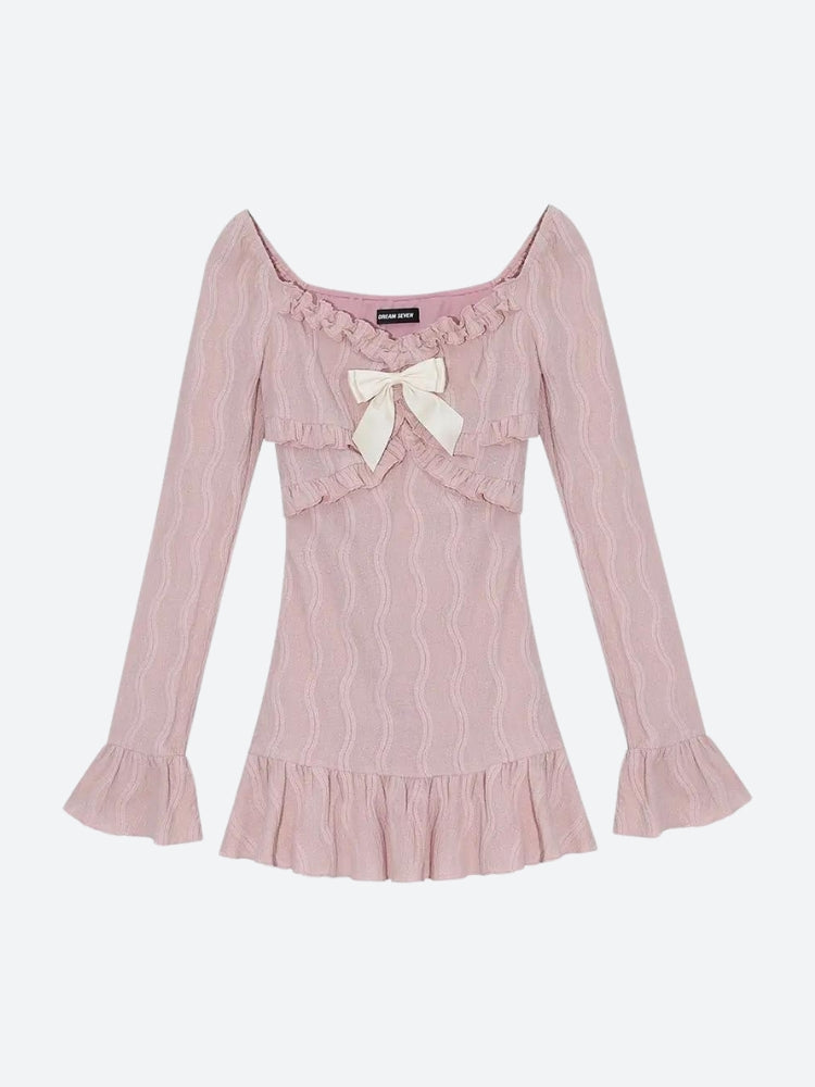 A pink dress with a bow, ruffles, and flared sleeves laid flat.