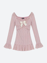 A pink dress with a bow, ruffles, and flared sleeves laid flat.