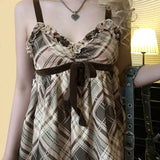 Close-up of the bodice of a brown and beige plaid babydoll dress with ruffled trim and a velvet bow.