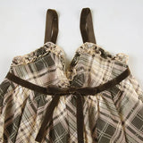 Close-up of the neckline and straps of a plaid babydoll dress with velvet trim.