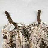 Close-up of the ruffled neckline and velvet straps of a plaid babydoll dress.