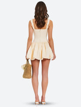The back of the cream-colored mini dress shows a zipper closure and the distinct bubble hem.
