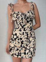 woman wearing a black floral print mini dress with tie straps