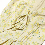 Close-up of the floral print and tie detail on the yellow dress