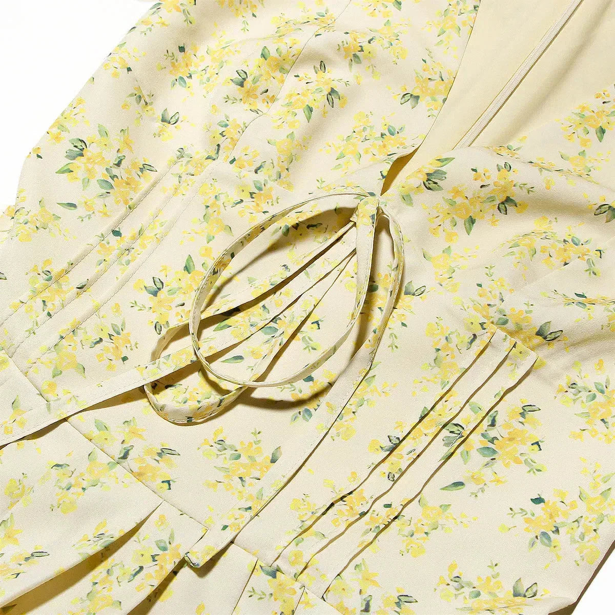 Close-up of the floral print and tie detail on the yellow dress
