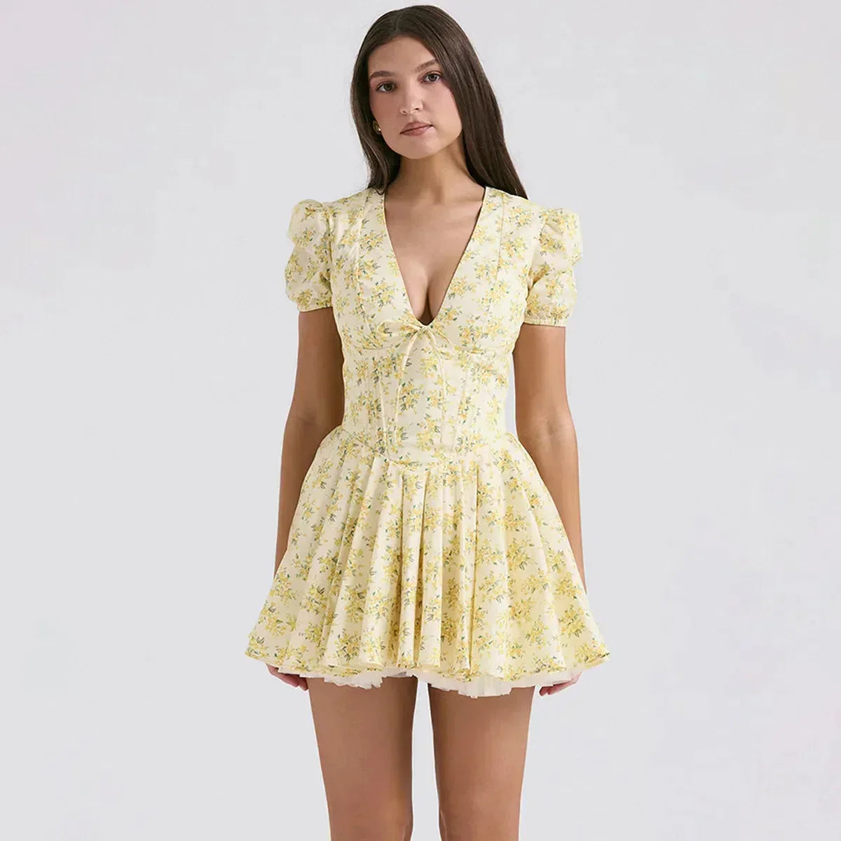 Woman wearing a yellow floral print mini dress with puff sleeves and a pleated skirt