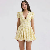 Woman wearing a yellow floral print mini dress with puff sleeves and a pleated skirt