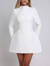 Front view of a woman wearing a white long-sleeved dress with a high neckline, flared skirt, and pocket details