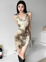 A woman poses in a beige and brown tie-dye mini dress with a hooded cowl neck and distressed detailing.