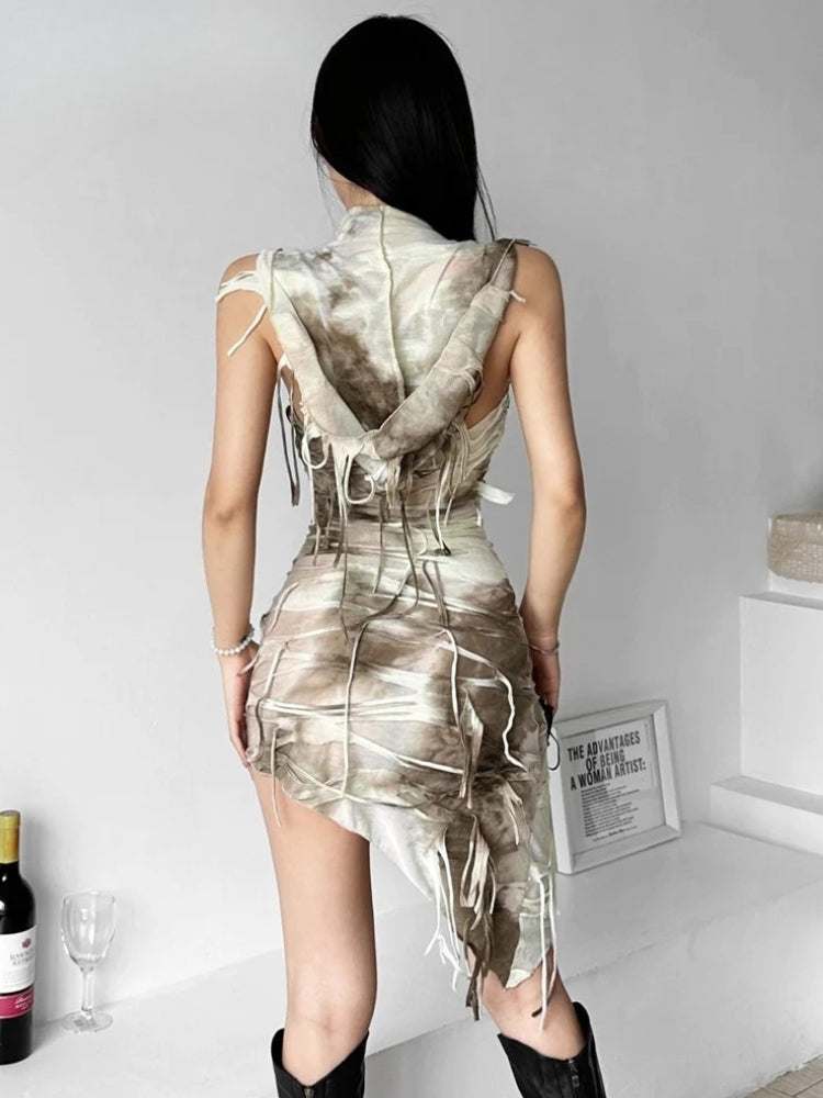 Back view of a woman in a beige and brown tie-dye mini dress with a hooded cowl neck and distressed detailing.