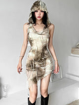 A woman models a beige and brown tie-dye mini dress with a hooded cowl neck and distressed detailing, paired with black boots.