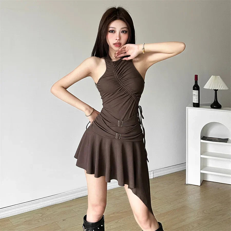 Woman striking a pose in a brown ruched halter dress with an asymmetrical hem and buckle details.