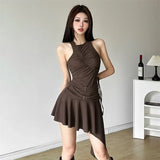 Woman wearing a brown ruched halter dress with an asymmetrical hem and buckle details.