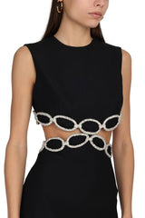Close-up of a black sleeveless dress with cut-outs and silver chain embellishments at the waist.