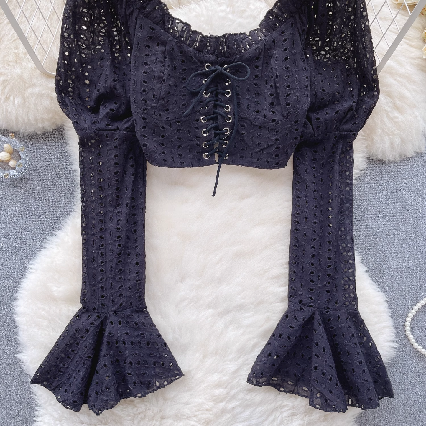 Detailed view of the black eyelet lace crop top's intricate eyelet pattern and bell sleeves.