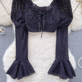 Detailed view of the black eyelet lace crop top's intricate eyelet pattern and bell sleeves.