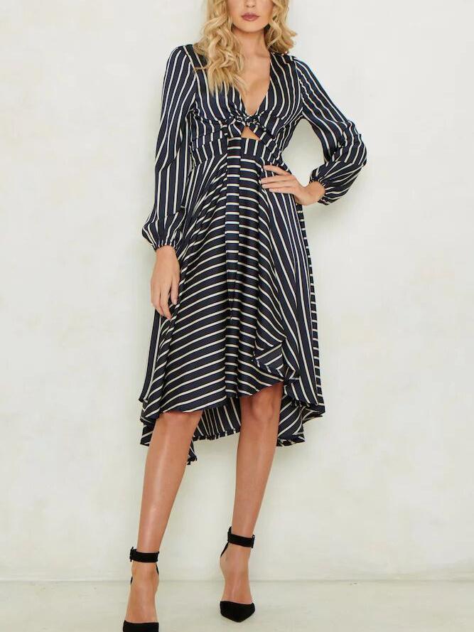 Full shot of a woman in a striped dress, posing with hands on hips