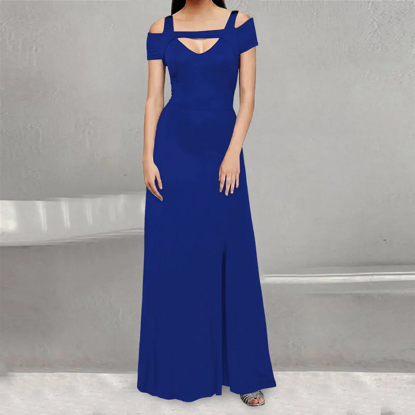 A woman wearing a royal blue floor-length dress with cold shoulder sleeves and a high slit.